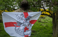 British soldier holding a St. George flag with a design of St George riding a horse against the dragon.