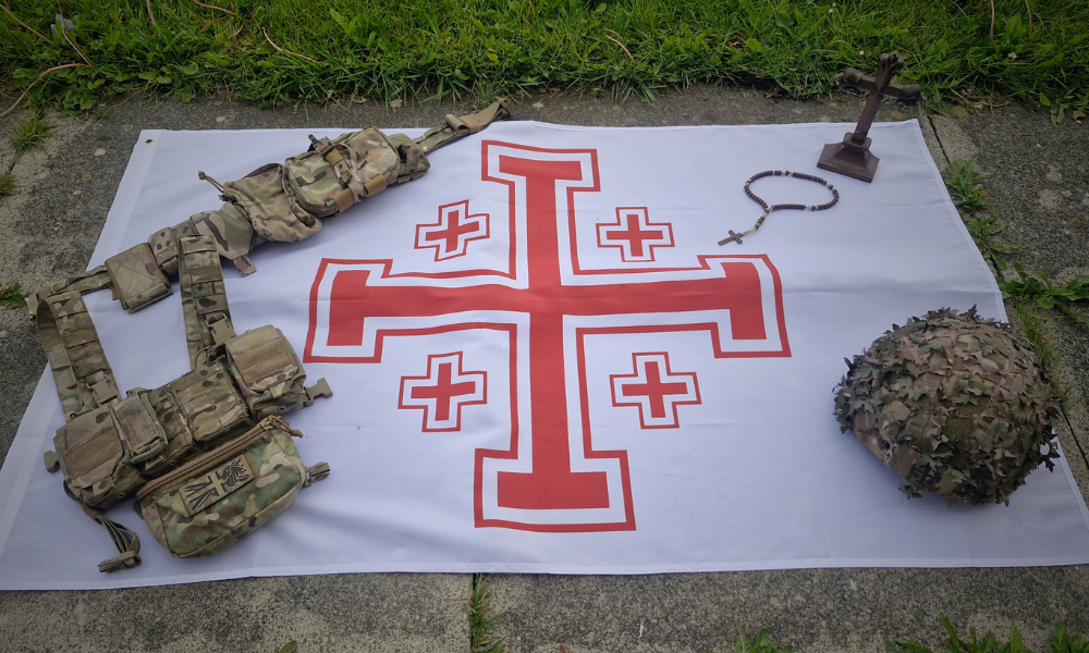 Jerusalem Cross flag with British soldier kit lay on it and a gothic cross with rosemary beads.