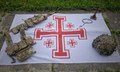 Jerusalem Cross flag with British soldier kit lay on it and a gothic cross with rosemary beads.